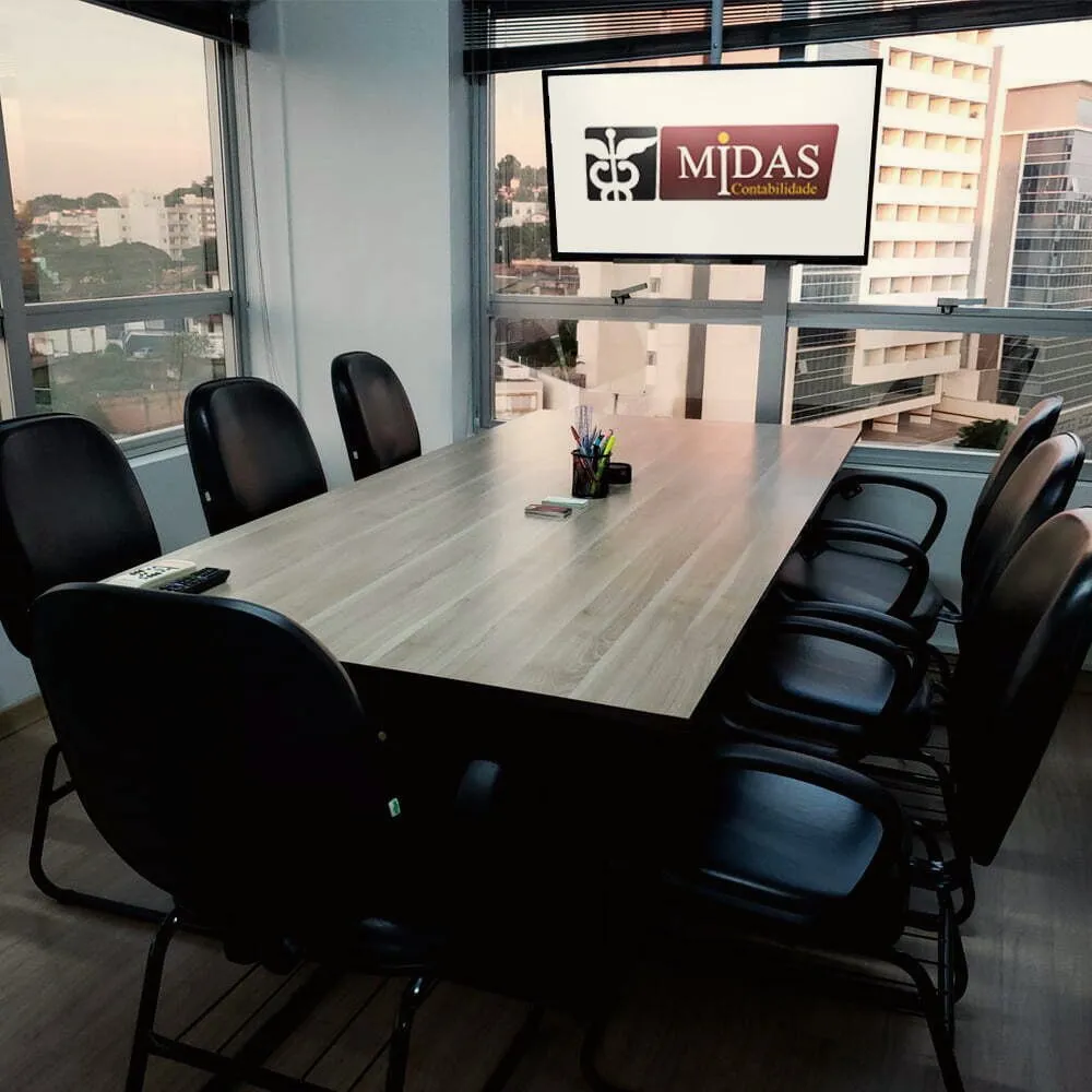 Sala de reunião com o logo da Midas na tela